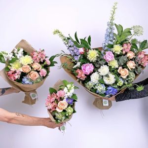 Three sizes of mixed flower bouquets held up against a white background