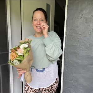 Smiling woman receiving a bunch of flowers at her door