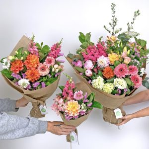Three sizes of mixed bouquets held up to show Little, Large, and Luxe options