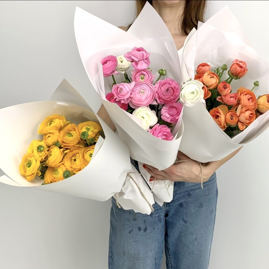 Bunches of ranunculus in yellow, pink and orange hues showing ruffled petals and layers