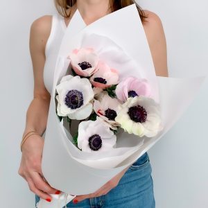 Close-up of a seasonal bouquet of anemones wrapped in white pape