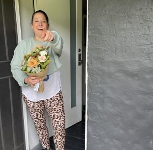 Smiling woman receiving a bouquet at her door.