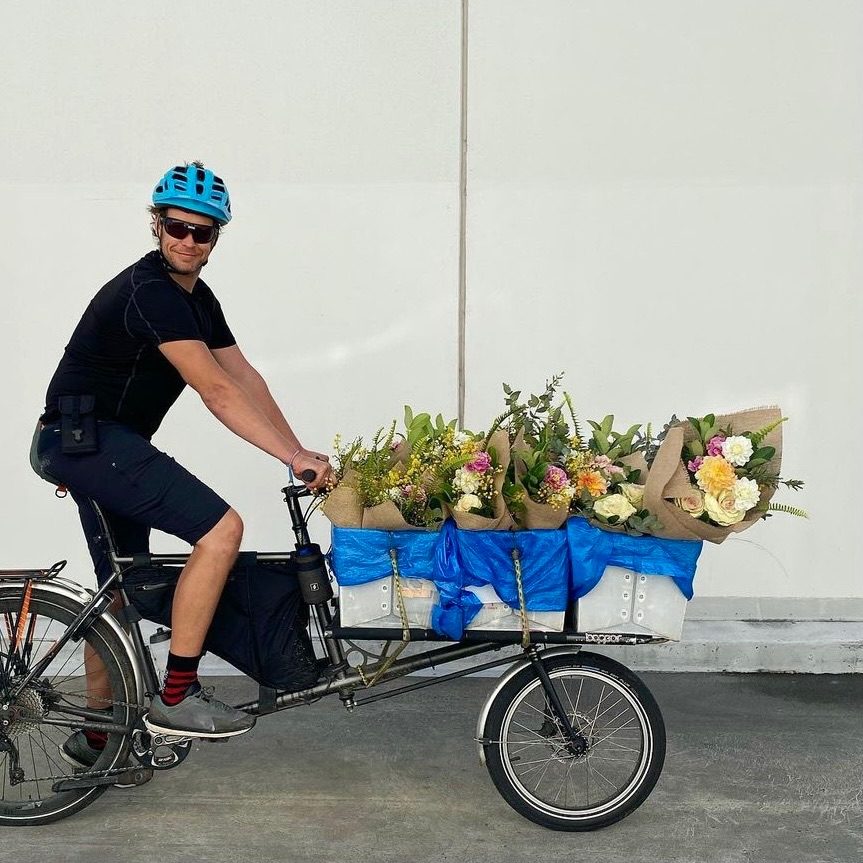 Bike courier smiling while transporting bunches of flowers