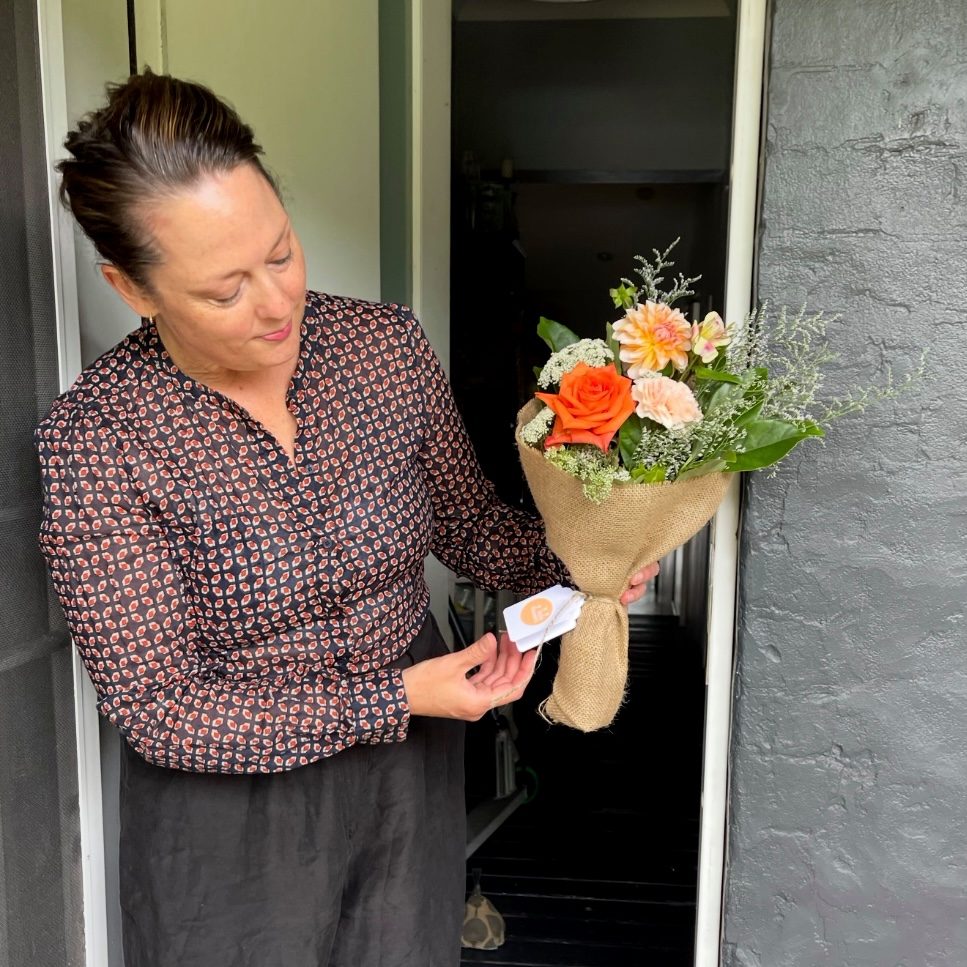 Woman reading a tag on a bunch of flowers at her front door