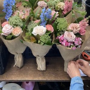 Florists wrapping daily mixed bouquets at a wooden bench