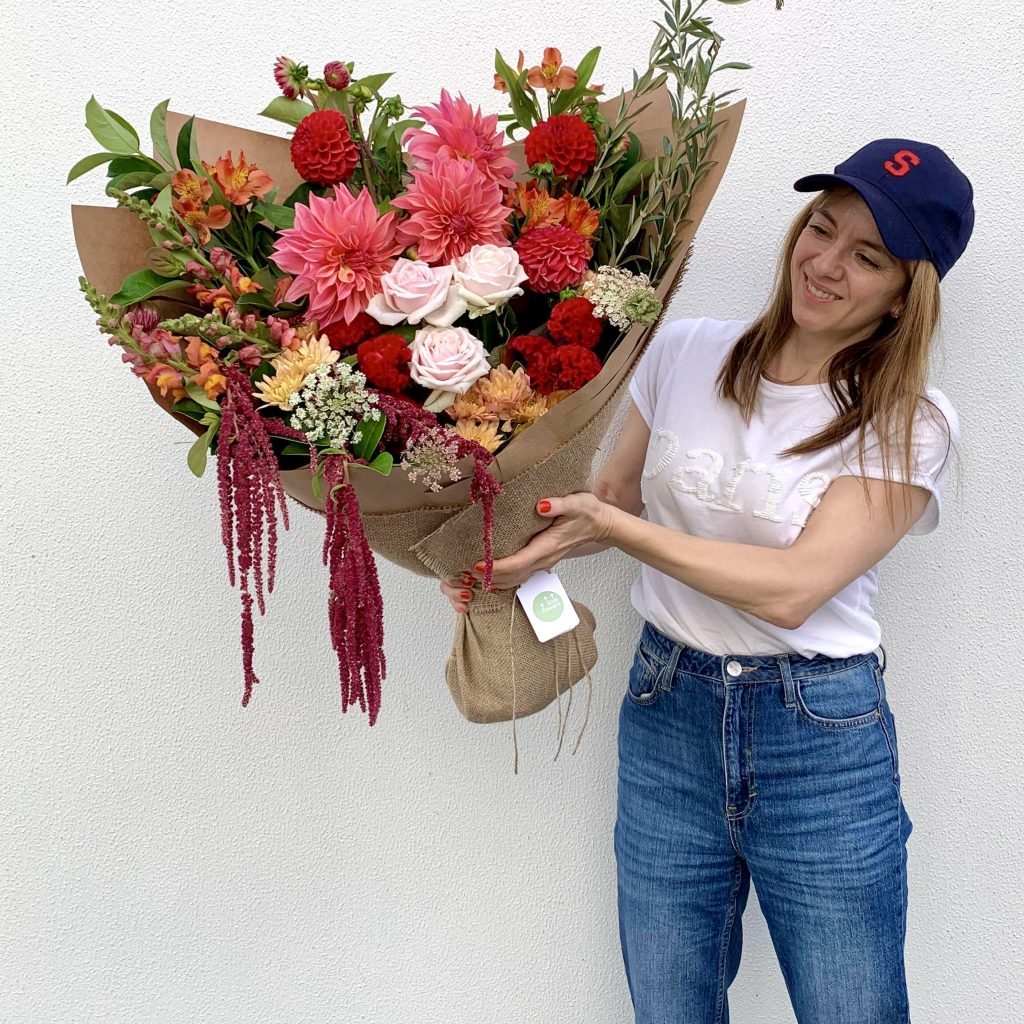 Woman holding Luxe bunch in rich red, gold, and blush tones