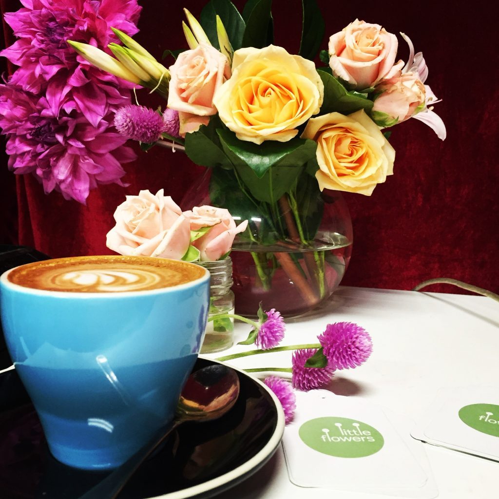 A takeaway coffee and a Little Flowers bunch on a café table