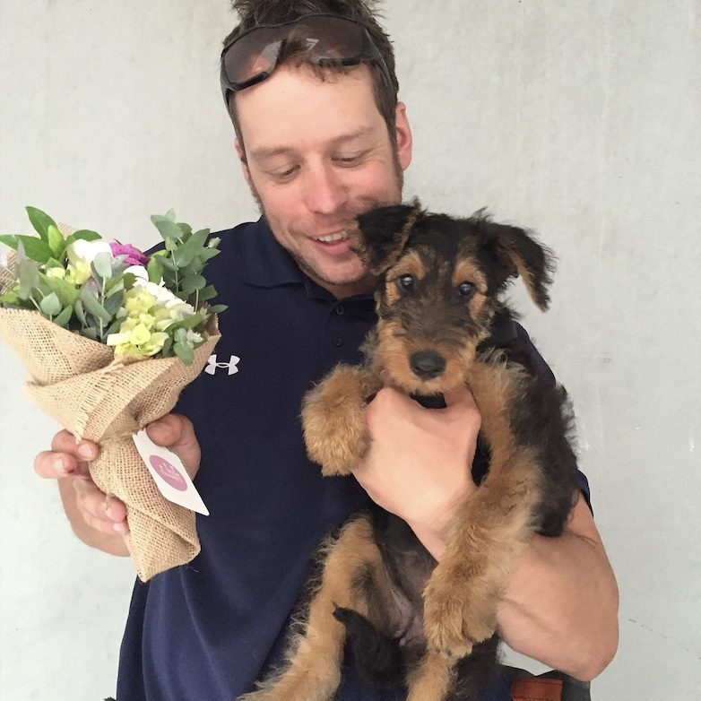 man holding dog and little flower bouquet