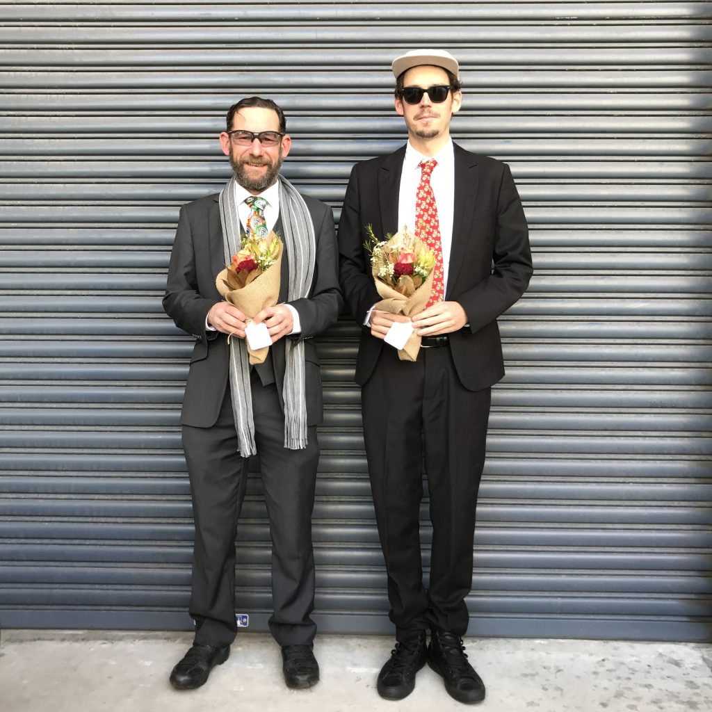 men in suits holding small flower bouquets