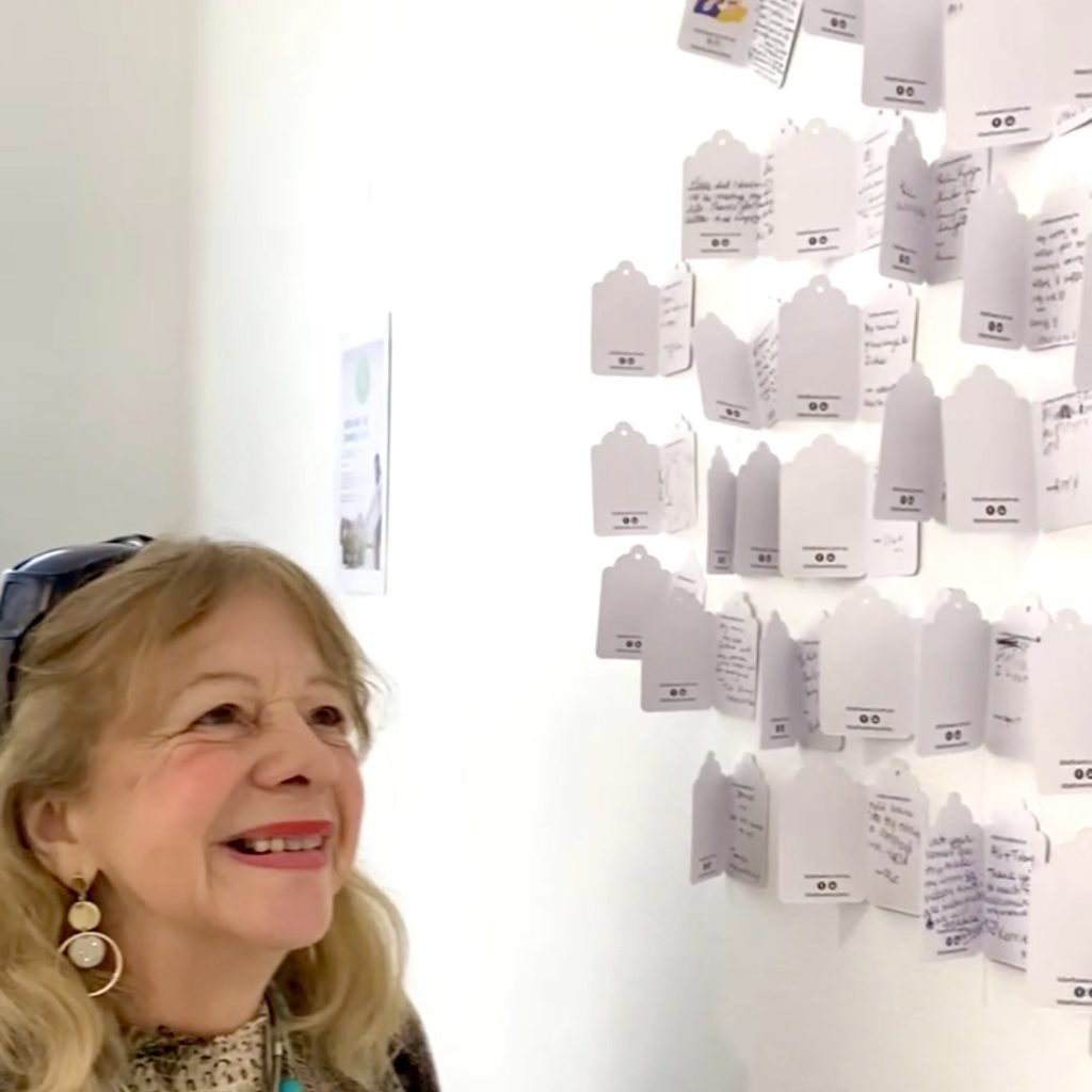 Smiling woman reading messages on the Gratitude Wall