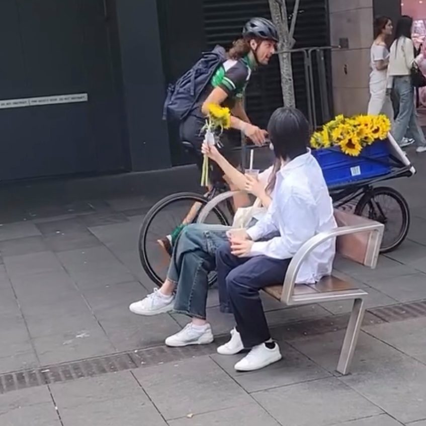 Courier handing sunflowers to stranger in Sydney CBD