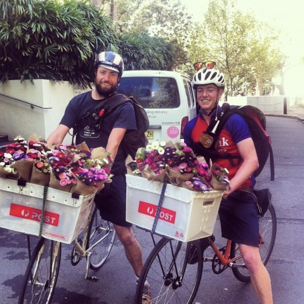 Two bike couriers with bunches in front crates